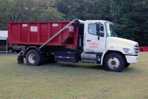 White roll-off garbage truck with red dumpster